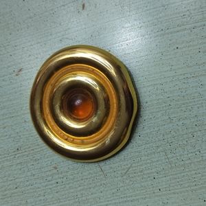 Gold colored circular brooch